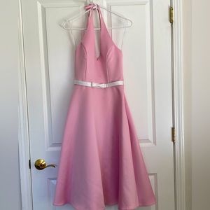 Pink halter neck bridesmaid dress with an a-line skirt and white bow detail
